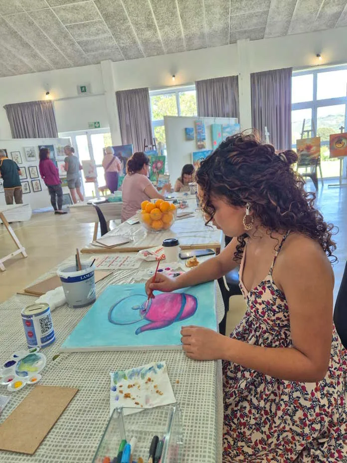 A visitor painting at the Plett Arts Association Communitty Hall exhibition 2025. Image supplied by PR company.